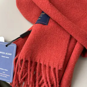Detail of Angola red wool scarf with fringe and classic woven label showing soft texture