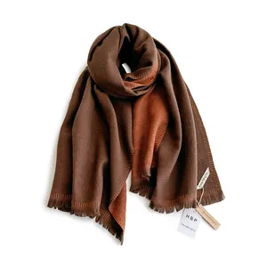 Detail of double-sided knit scarf with fringe in dark brown and burnt orange hues