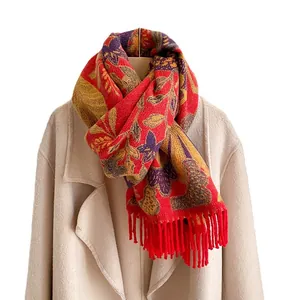 Châle ethnique rouge à fleurs avec franges sur un manteau beige pour l'hiver chaud