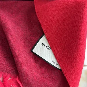 Detailed macro view of dark red wool scarf with fine knit texture and fringe edge