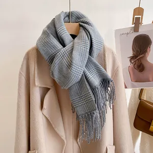 Detail showing soft light blue plaid scarf texture with long fringe on a warm coat