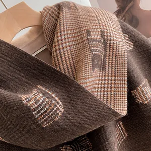 Detail of soft houndstooth cashmere scarf with cat jacquard and thick fringed texture