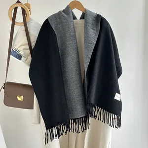 Detail of wool blend scarf with fringe edges and rectangular label on white wall