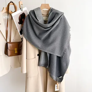 Close-up of grey knit cashmere scarf with fine rib stitch and fringe details on coat