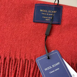 Detailed close-up of dark red wool scarf texture with neat fringes and woven brand label