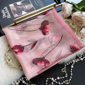 Pink silk blend scarf with tulip floral embroidery and beadwork on a luxury tray