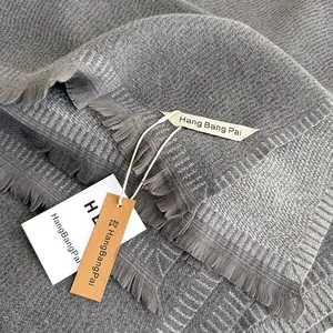 Close-up of gray knit scarf with honeycomb texture and elegant fringe tassels
