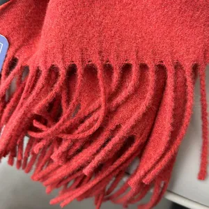 Detailed close-up showing the soft wool texture and tassel fringe of the red winter scarf