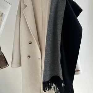 Close-up of thick grey wool scarf with fringe and cream double-breasted wool coat