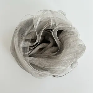 Close-up of silver-grey organza scarf fabric with semi-transparent texture and metallic luster