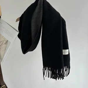 Detail of wool blend scarf with fringe edges and dual-sided black and grey color design