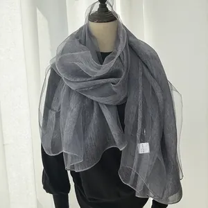 Close-up of grey translucent mesh scarf showing light pleated texture and wavy edges