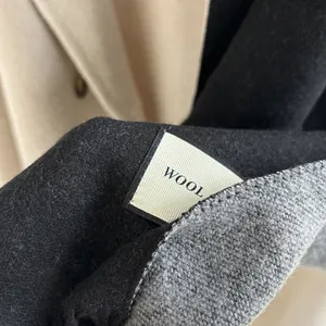 Detailed macro shot of premium wool fiber texture and wash label on two-tone scarf