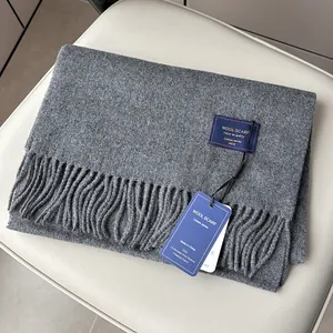 Macro detail of dark grey wool scarf featuring fine fringe and branded woven label