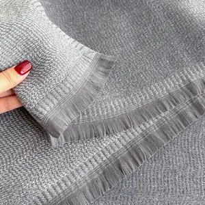 Close-up of gray cashmere-like scarf showing fine woven texture and tassel fringes