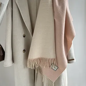 Close-up of beige wool scarf with fringe detail and luxury handmade quality label
