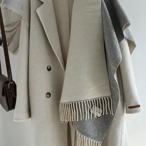 Detail of wool coat with hand made label and matching long tassel scarf in beige