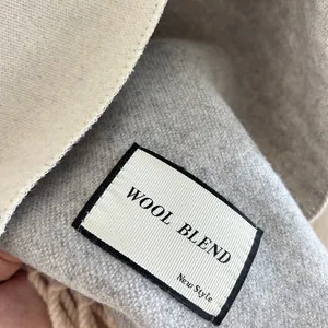 Detailed macro view of the grey wool blend fabric texture and the woven logo label