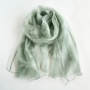 Detail of light green semi-transparent silk scarf with soft sheen and delicate texture