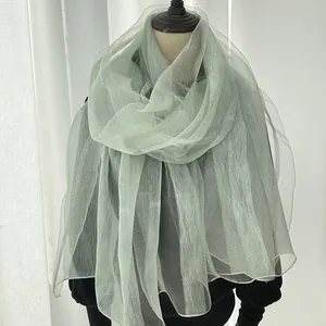 Detail of light green silk scarf showing transparent texture and soft drape on mannequin
