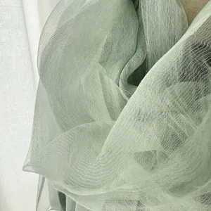 Detail shot of light green pleated silk scarf featuring premium translucent mesh texture