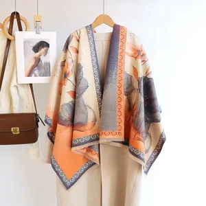 Detail of floral cashmere-like shawl with fringed edges draped over a stylish light coat