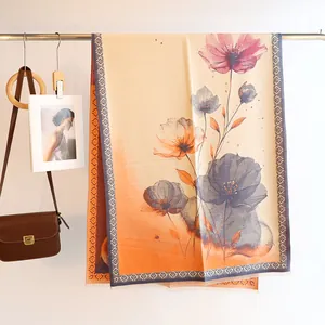 Detailed view of beige and orange gradient scarf with floral print and fine tassel fringe