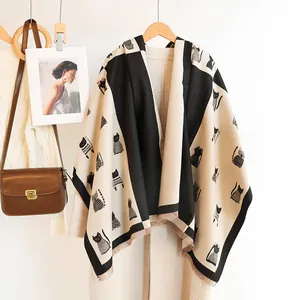 Beige and black knit shawl with cute cat illustrations and tassel trim details