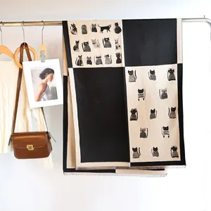 Detail of checkered cat pattern scarf with tassels hanging on a hanger against a white wall