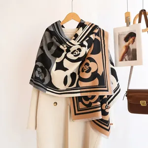 Detail of camellia print scarf with fringe edges draped on an ivory coat