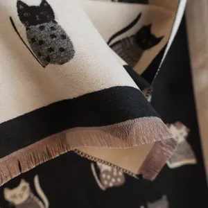 Close-up of thick cat jacquard knit scarf showing elegant black and white fringe details