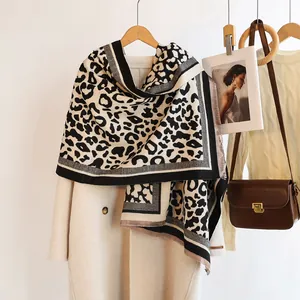 Detail of leopard print scarf with tassels over beige coat and vintage leather bag