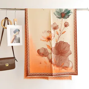 Detail of floral cashmere-like scarf with blue and orange watercolor print and fringe