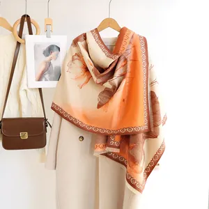 Detail of soft orange floral cashmere feel shawl with tassels on a white wool coat
