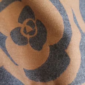 Detailed close-up showing the soft cashmere texture and grey camellia pattern of the scarf