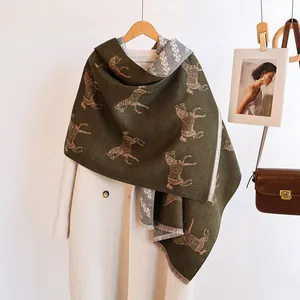 Detail of moss green cashmere-feel scarf with horse jacquard and delicate fringe