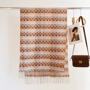 Detailed close-up of earth-tone plaid scarf with soft tassels hanging on a metal rack