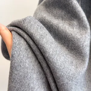 Close-up of soft grey wool fabric texture showing the thick material and warm fringe detail