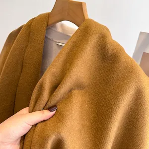 Close-up of caramel wool shawl fabric showing soft thick texture and woven label