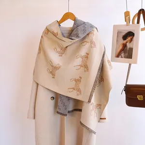 Close-up of double-sided horse jacquard scarf with beige grey fringe and soft texture