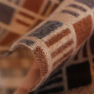 Macro shot of plaid tassel scarf showing soft plush texture and earth-toned geometric pattern