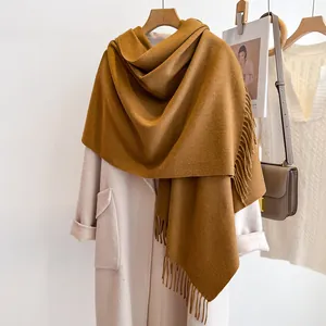 Close-up of caramel wool scarf tassels and soft fabric texture on a beige coat