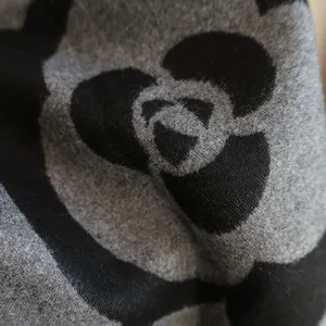 Detailed macro view of the thick camellia jacquard pattern on a soft cashmere-like scarf