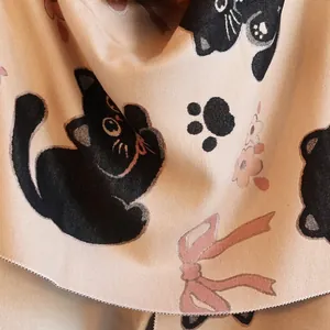Gros plan d'une écharpe beige douce avec motifs de chats noirs et nœuds roses