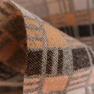 Close-up of warm orange and brown plaid fabric texture on a soft winter scarf