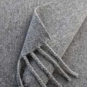 Macro shot of grey wool scarf showing soft fiber texture and woven fringe details