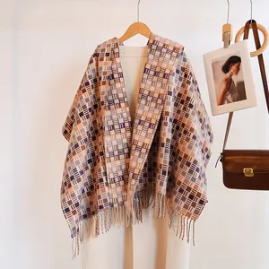 Detail of plaid tassel scarf in caramel and blue draped on a coat with wooden hanger