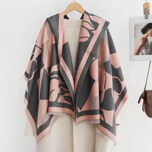 Detail van een gebloemde kasjmier sjaal met franjes op een elegante beige jas