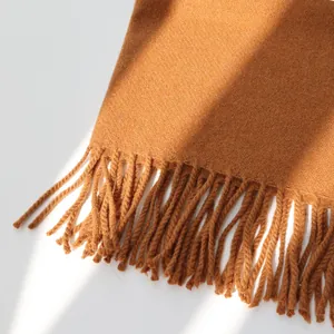Detailed macro shot of caramel wool scarf featuring delicate twill texture and fringe