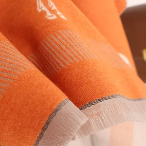 Gros plan d'une écharpe orange aspect cachemire avec motif cheval jacquard et franges